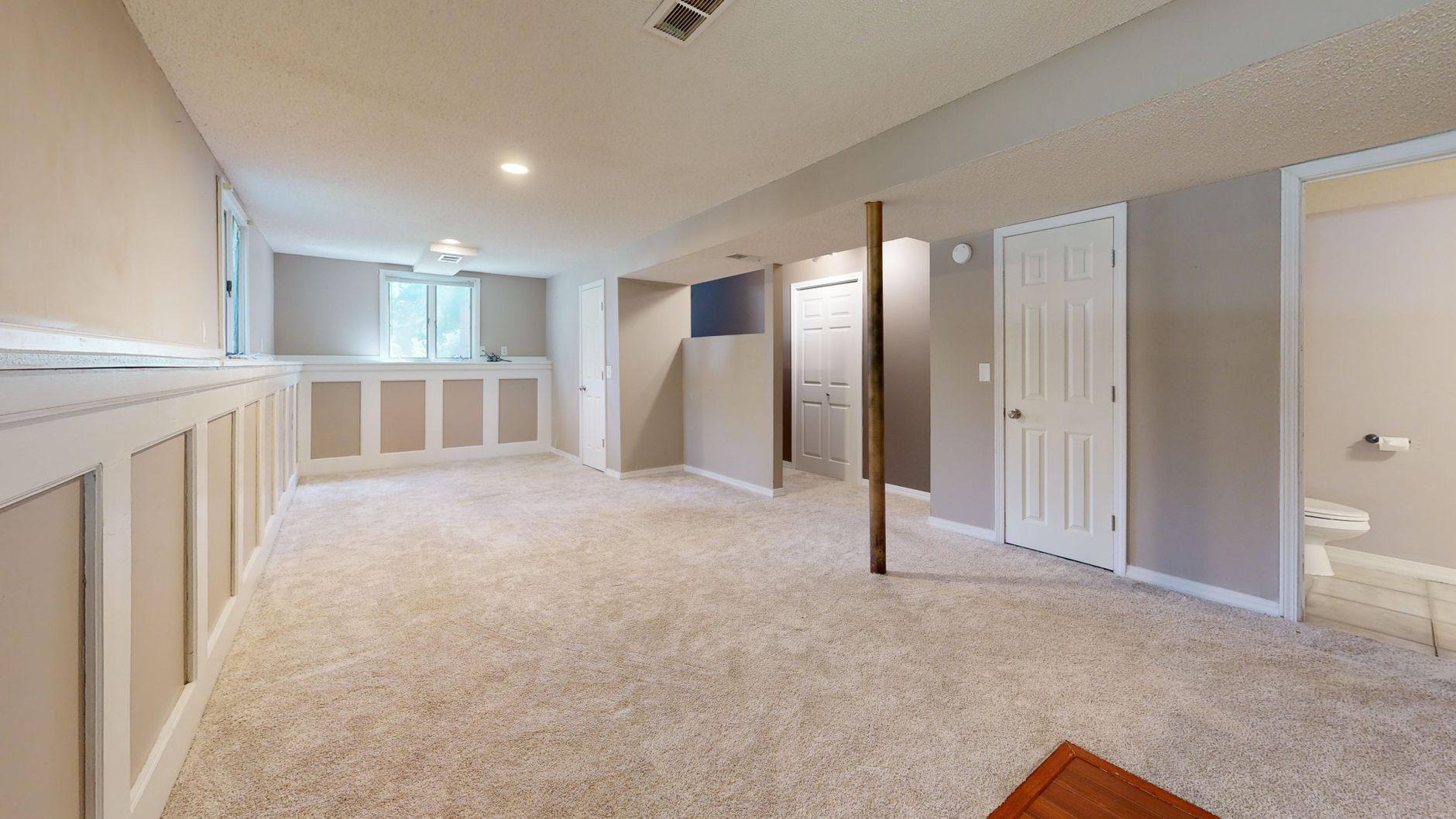 Bright and clean modern basement with carpet flooring and recessed lighting