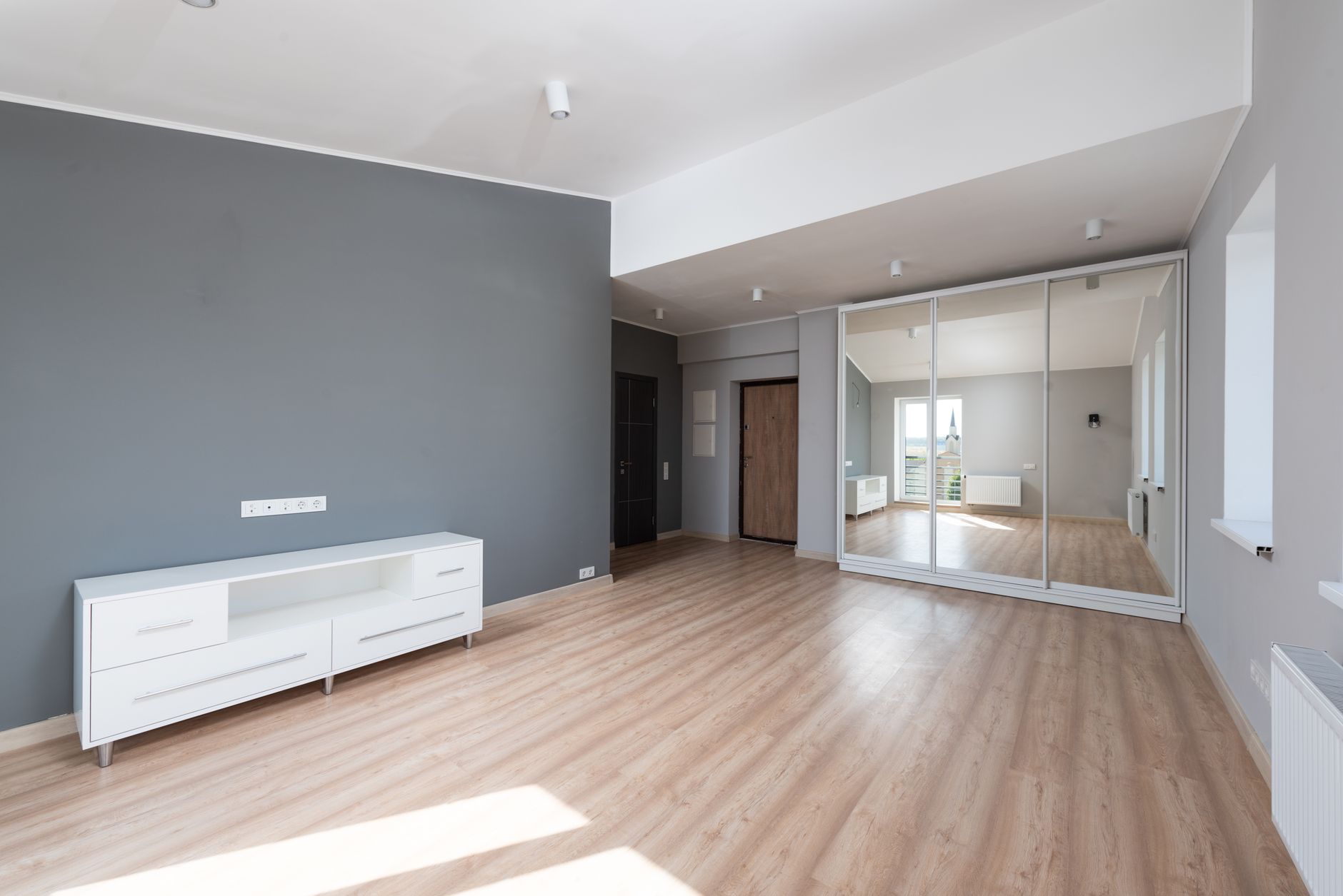 Spacious empty room with wooden flooring and minimalist style furniture